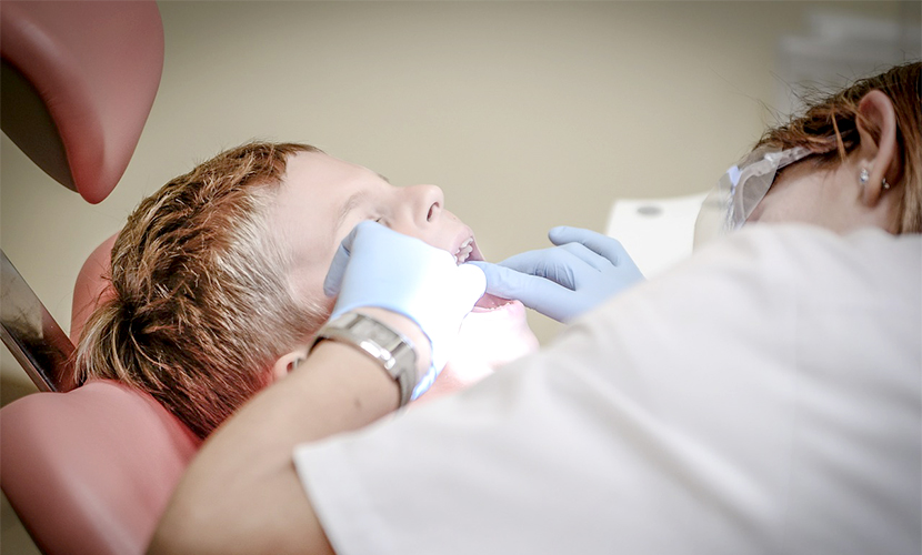 Zahnärztin behandelt Kind mit Sandstrahlgerät dental